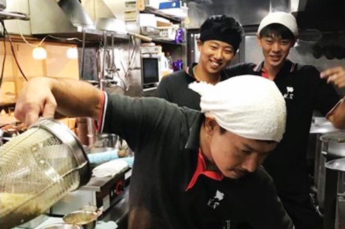 平九郎Rの厨房で湯切りをするスタッフと仲間たち