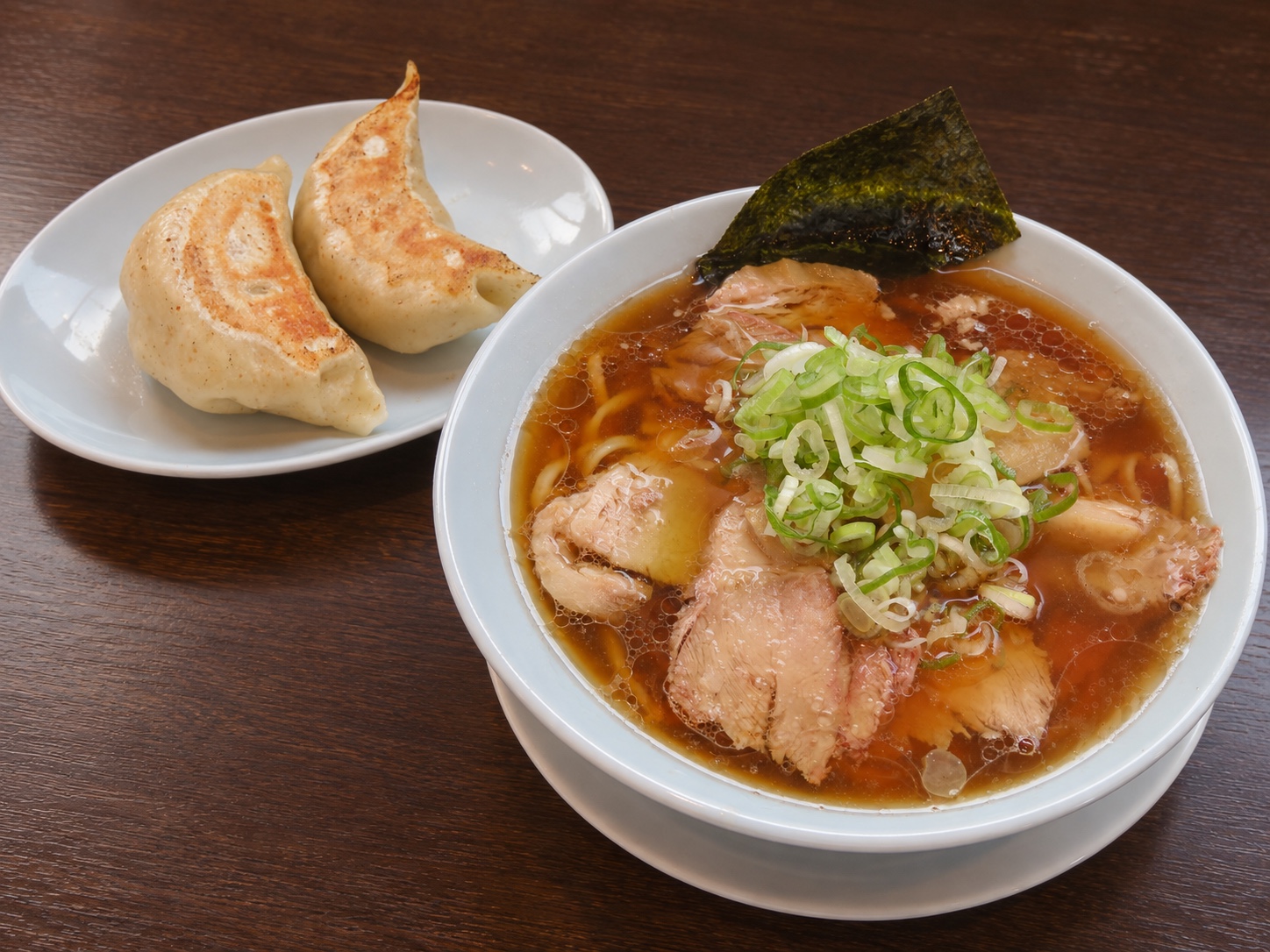 餃子のしのちゃんの白い器の中華そばと、大きな焼き餃子2個の盛り付けイメージ
